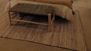 A bedroom with a large bed, a wooden headboard, two bedside tables, and a bench.