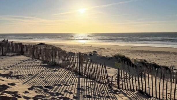 A beach with a wooden fence and a clear sky.