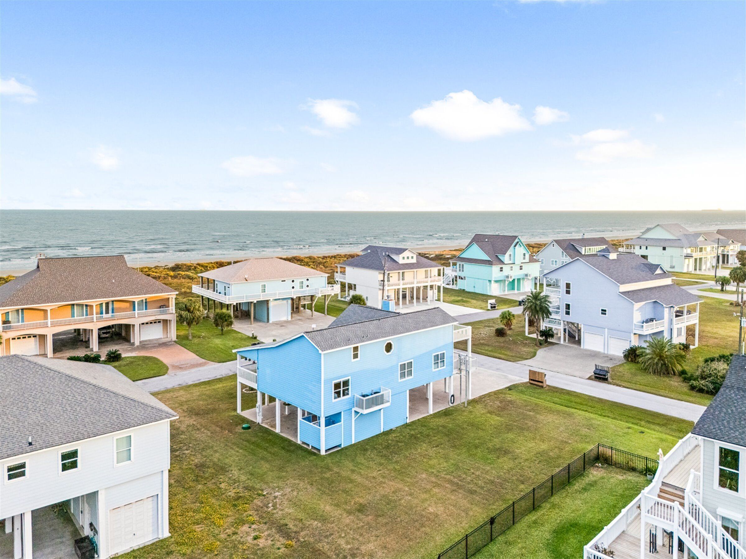 A coastal residential area with houses featuring balconies and a view of the ocean.