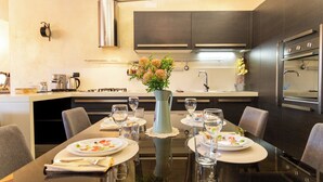 Una cocina moderna con armarios oscuros, una isla central y una mesa de comedor dispuesta para seis comensales.