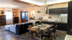 Una cocina moderna con armarios oscuros, una isla central y un comedor con una mesa y sillas de vidrio.