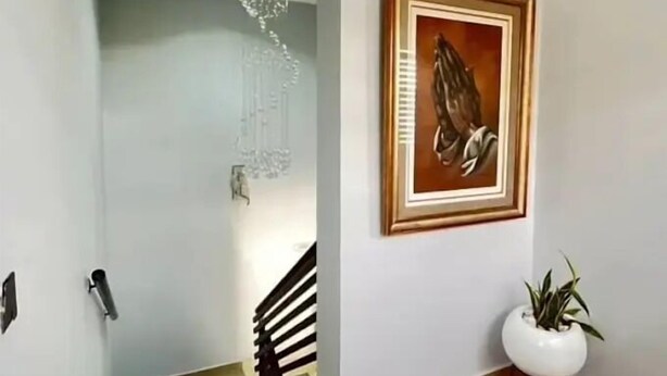 A hallway with a staircase, a framed artwork on the wall, a potted plant, and a red bowl on the floor. - Starwave Homes (Abuja)