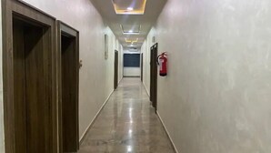 A hallway with wooden doors on the left, a fire extinguisher on the right, and a tiled floor. - Starwave Homes (Abuja)