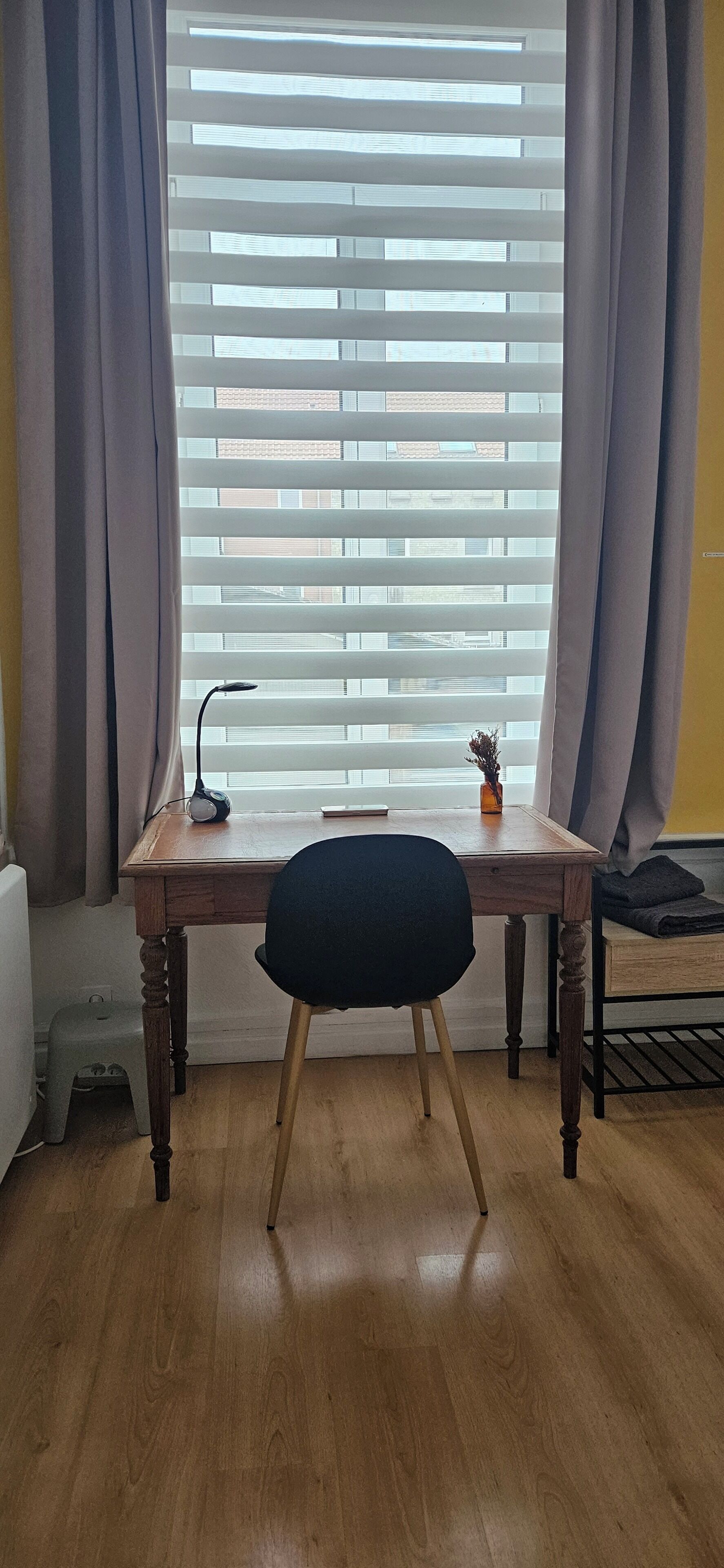 A wooden desk with a chair, a lamp, and a small plant.