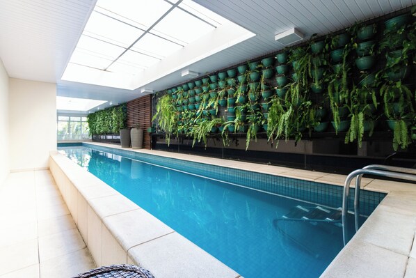 Una piscina al aire libre, sombrillas, sillones reclinables de piscina