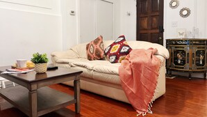 A living room with a beige sofa, a wooden coffee table, a small plant, and a decorative pillow. - Ramblei near Rittenhouse Sq / 2 bedroom – Unit B (Philadelphia)