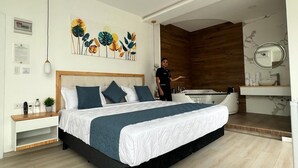 Een moderne slaapkamer met een groot bed, een houten hoofdbord, een ingebouwd ligbad en een kaptafel met spiegel.