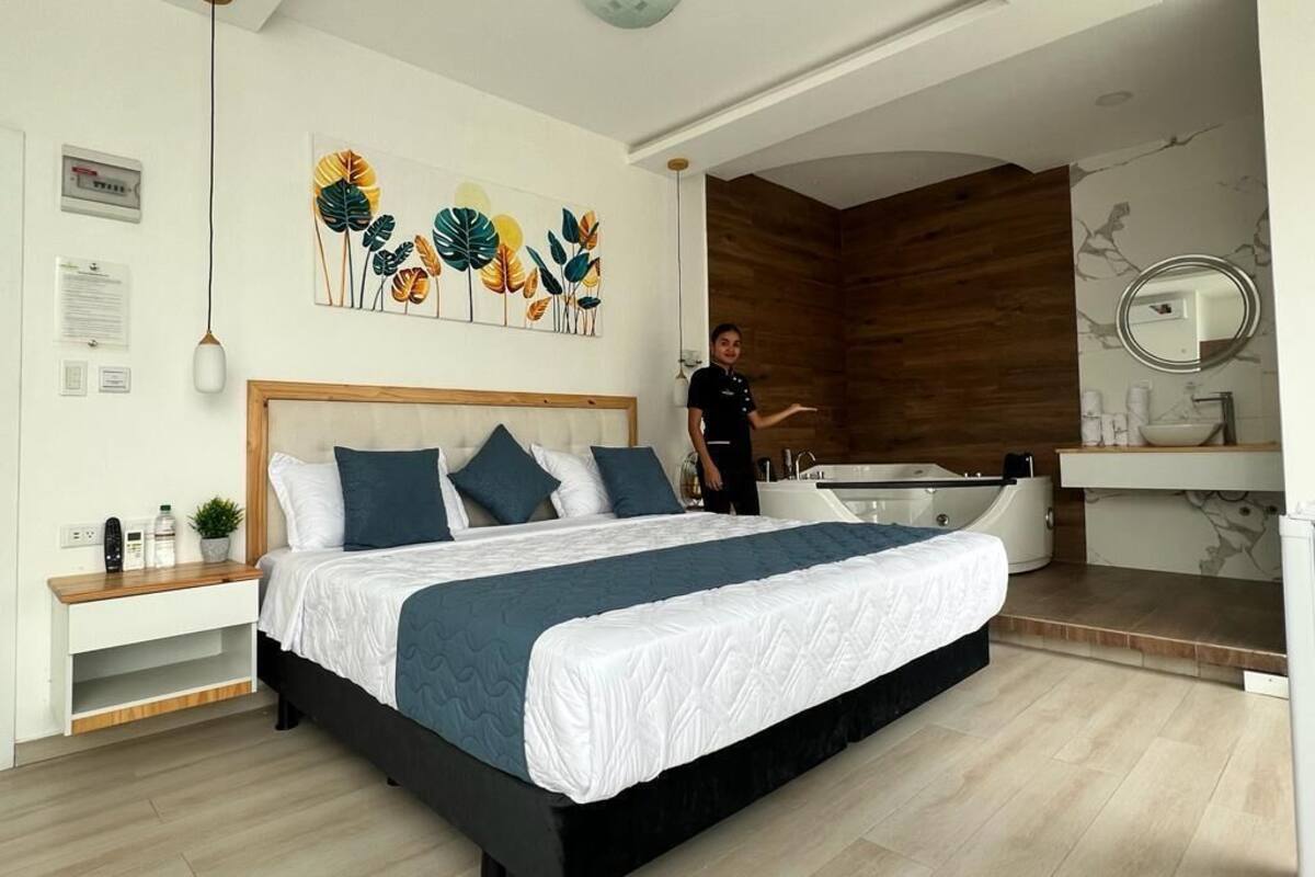 Un dormitorio moderno con una cama grande, cabecera de madera, bañera integrada y tocador con espejo.