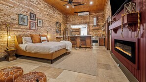 A cozy bedroom with a bed, a desk, and a fireplace.