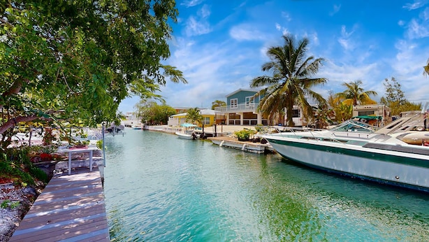 A waterfront property with a dock, a boat, and a house with a balcony overlooking the water. - Big Pine Turtle House (Big Pine Key)