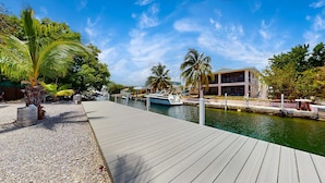 A wooden dock extending over calm water, with a boat docked nearby. - Big Pine Turtle House (Big Pine Key)