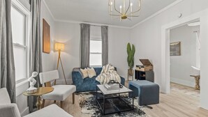 A modern living room with a blue sofa, a coffee table, and a chandelier.