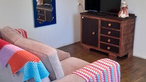 A living room with a sofa, a television, a wooden cabinet, and a mirror on the wall.