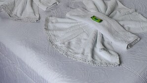 A neatly made bed with white linens and a decorative towel arrangement.