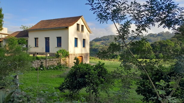 A two-story house with a tiled roof, a stone foundation, and a small arched entrance.