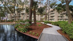 Un espace paysager agrémenté d’un élément aquatique, de sentiers et d’immeubles à plusieurs étages dotés de balcons.