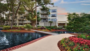 A hotel with a swimming pool, landscaped garden, and multi-story buildings.