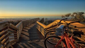 Une promenade en bois menant à une plage, avec un vélo garé dessus.