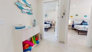 Una habitación de hotel con cama, escritorio y estante con toallas de colores.