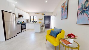 Una cocina moderna con electrodomésticos de acero inoxidable, una isla central y un sofá amarillo brillante en un amplio salón.