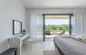 Une chambre moderne avec un lit, un bureau et un balcon équipé de chaises.