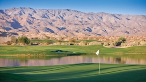A golf course with a flagstick, water hazards, and a mountainous backdrop. - Desert Oasis: Spacious 2-Bedroom Suite at Club Wyndham Indio (Indio)