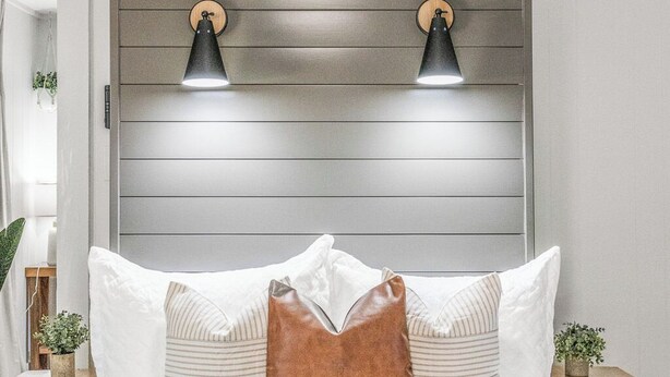 A bedroom with a bed, two wall-mounted lamps, a ceiling fan, and a wooden headboard. - The P'Cola Sunrise. 1 bed 1 bath cottage (Pensacola)