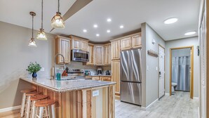 A modern kitchen with wooden cabinets, stainless steel appliances, and a central island with bar stools.