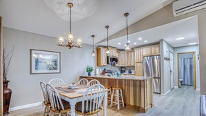 A modern kitchen with wooden cabinets, a central island, and pendant lighting.