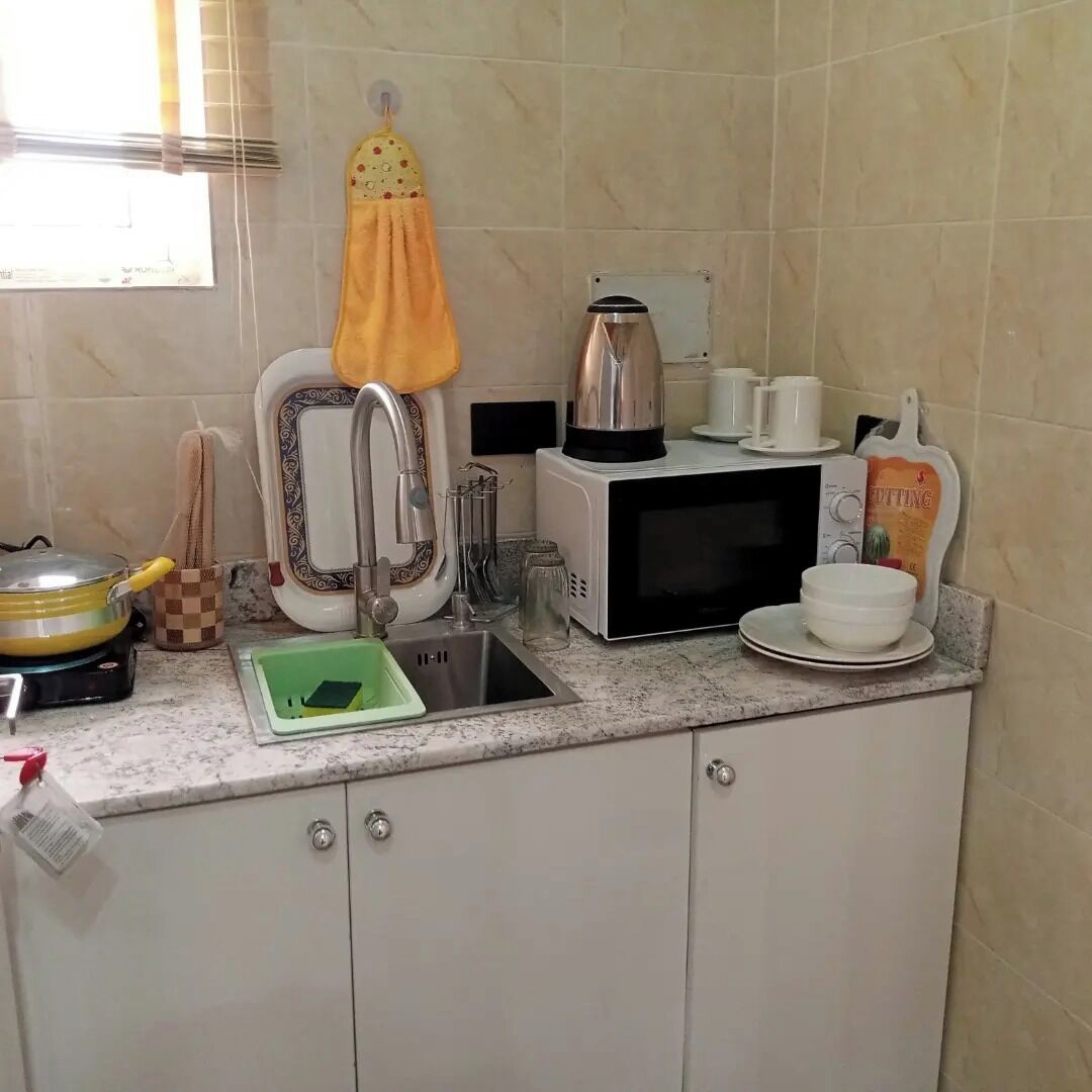 A kitchen with a sink, stove, microwave, and a window with blinds.