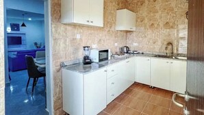 Una cocina moderna con armarios blancos, microondas integrado y un lavamanos.