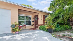 Il s’agit d’un bâtiment d’un seul étage, doté d’une façade beige, d’une porte d  ’entrée et d’un garage. On y trouve des plantes en pot et un petit espace extérieur aménagé avec une chaise rouge.