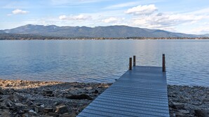 A wooden dock extending into calm water with mountains in the background.