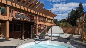 Area con vasca idromassaggio, una piscina e un edificio con un cartello che indica 'HOT TUBS OPEN'.
