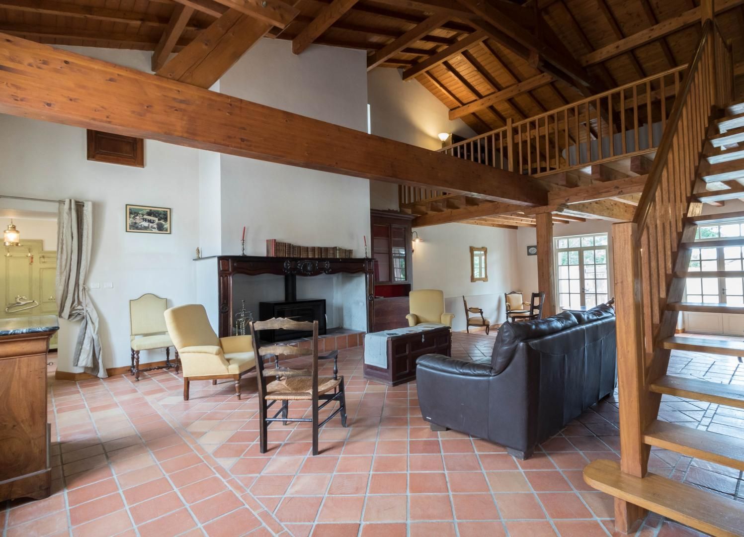 Un salon spacieux doté d’une cheminée, d’un escalier en bois et d’un plancher carrelé.