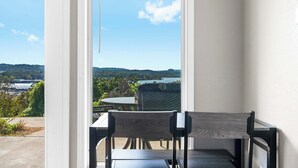 Een balkon met uitzicht op een meer en heuvels, een houten stoel en een tafel.