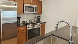 A modern kitchen with stainless steel appliances, wooden cabinets, and a stainless steel sink.