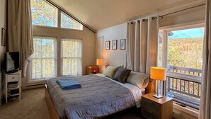 A bedroom with a large bed, a TV, a desk, and a window with curtains. - Marvelous 3-bedroom townhome in Hunter Mountain next to the slopes (Lanesville)