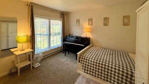 A bedroom with a bed, a piano, a desk with a lamp, a fan, and a window with curtains. - Marvelous 3-bedroom townhome in Hunter Mountain next to the slopes (Lanesville)
