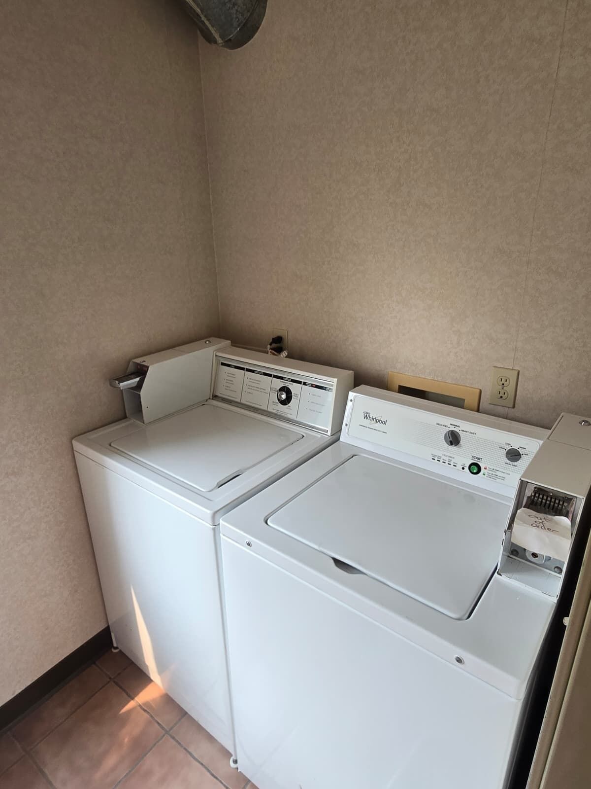 Een wasserette met twee witte Whirlpool wasmachines en drogers.
