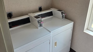 Ein kleiner Hauswirtschaftsraum mit einer Waschmaschine und einem Trockner, einem Fenster und einer fest installierten Steckdose.