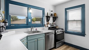 A kitchen with teal cabinets, a stove, a dishwasher, and a sink.