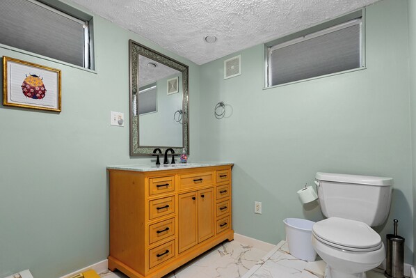 A bathroom with a wooden vanity, a white toilet, and a mirror.