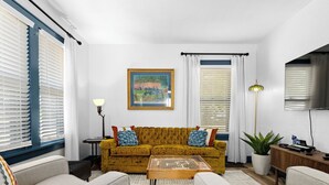 A living room with a sofa, a coffee table, and a painting on the wall.