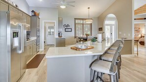 Una cocina moderna con una isla grande, electrodomésticos de acero inoxidable y un comedor con candelabro.