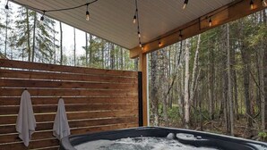 A hot tub in a wooden cabin with a forest view.