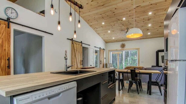 A modern kitchen with a wooden countertop, built-in appliances, and pendant lighting.