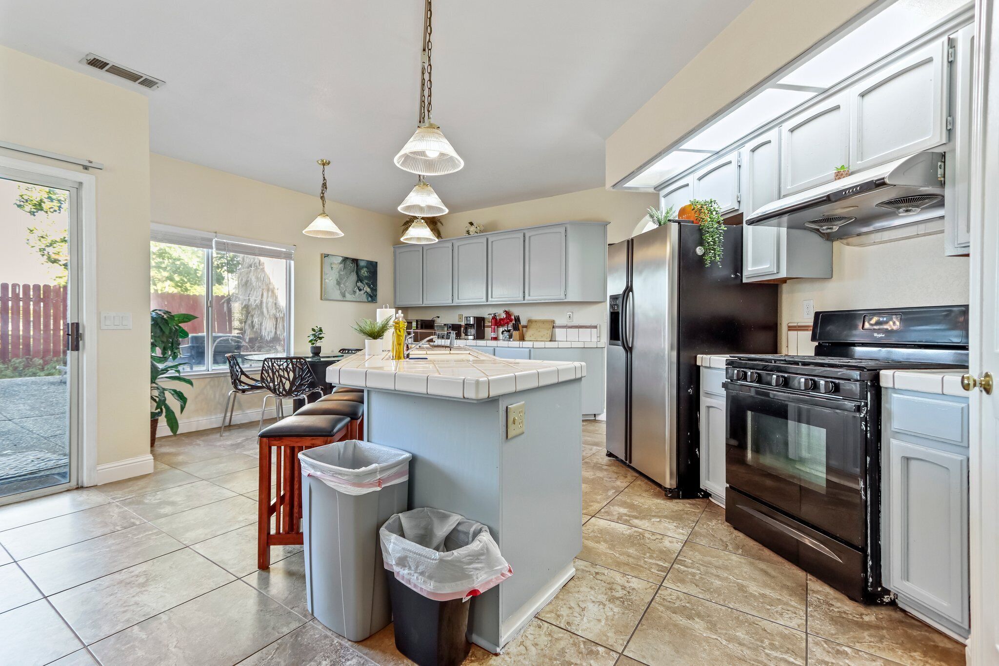 A spacious kitchen with a central island, stainless steel appliances, and pendant lighting.