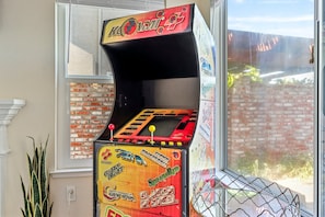 A vintage arcade machine with a brick wall and window in the background.