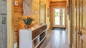 A wooden interior with a white console table, a plant, and a door leading outside.